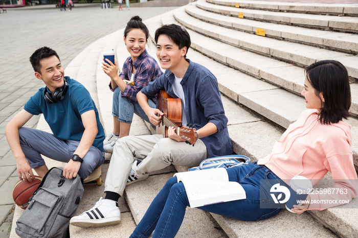 年轻的大学生坐在台阶上弹吉他