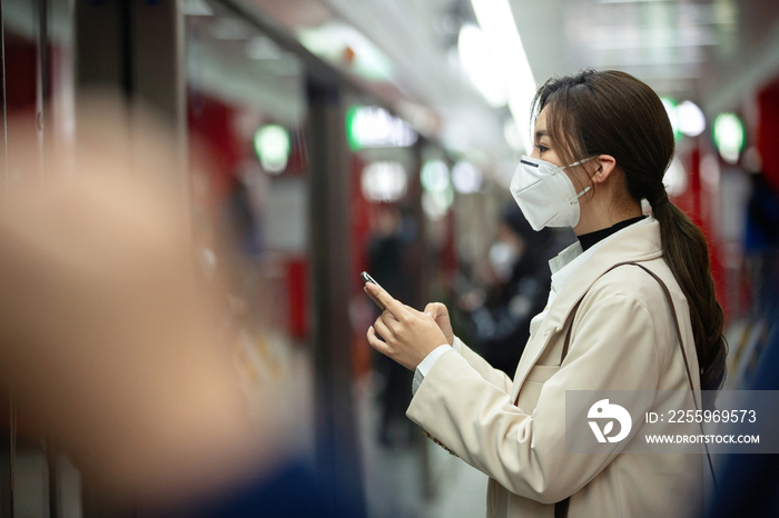 戴口罩的年轻女人站在地铁站台上