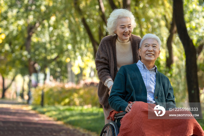 老年女人推着坐轮椅的老伴散步