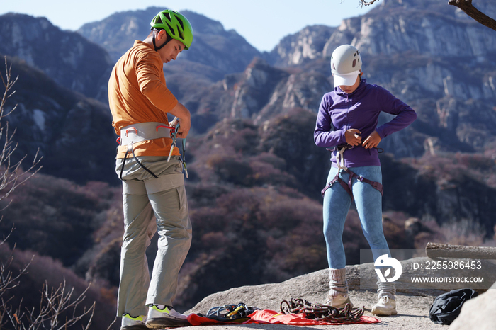 青年登山者伴侣调整登山设备