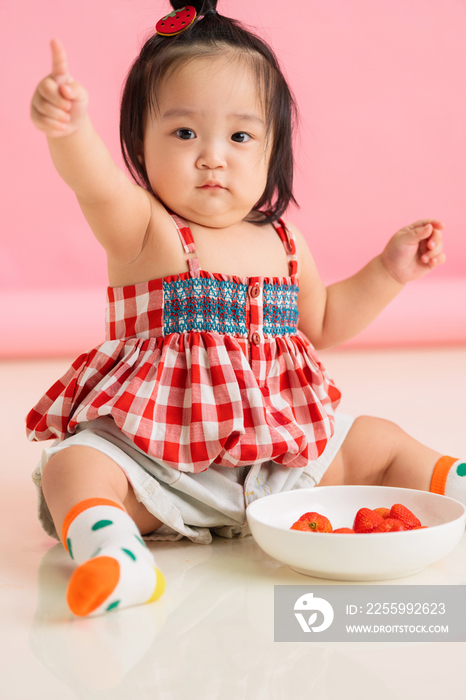 可爱的女宝宝坐在地板上吃草莓