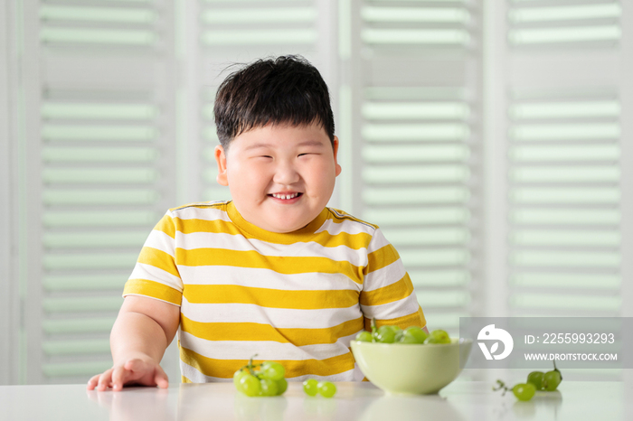 可爱的肥胖小男孩吃葡萄