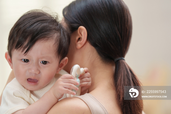 年轻妈妈抱着哭闹的宝宝