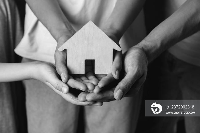 Hands of family with small house, closeup