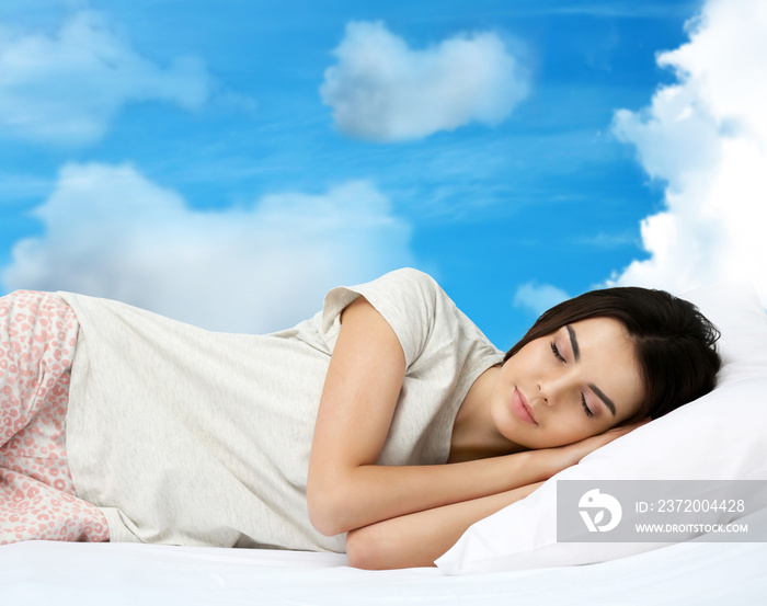 Young woman sleeping in bed and sky background