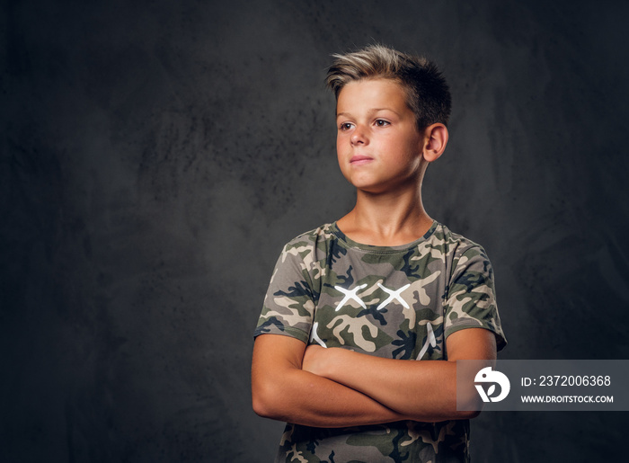 Little charming boy with nice hairstyle is posing over dark background at photo studio.