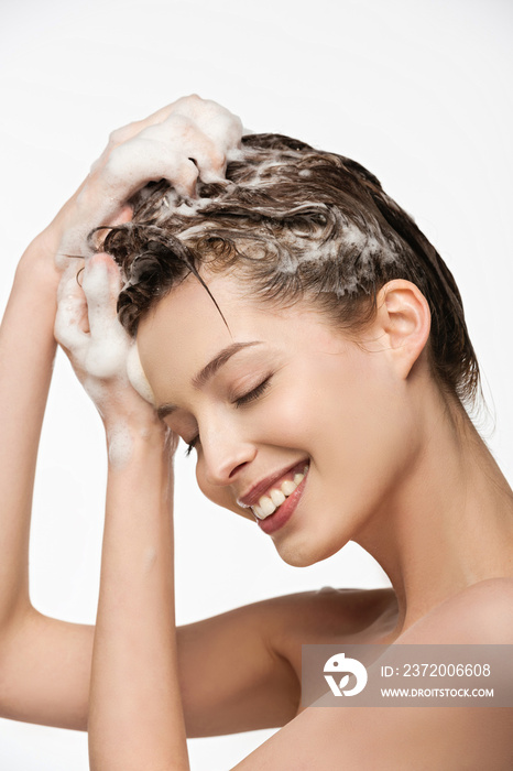 smiling girl washing hair with closed eyes isolated on white