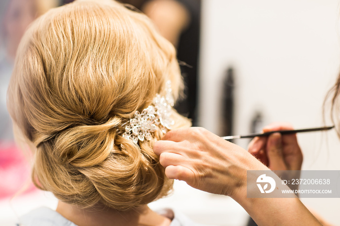 Hair stylist makes the bride before a wedding
