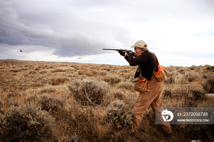 Hunter shooting bird in field