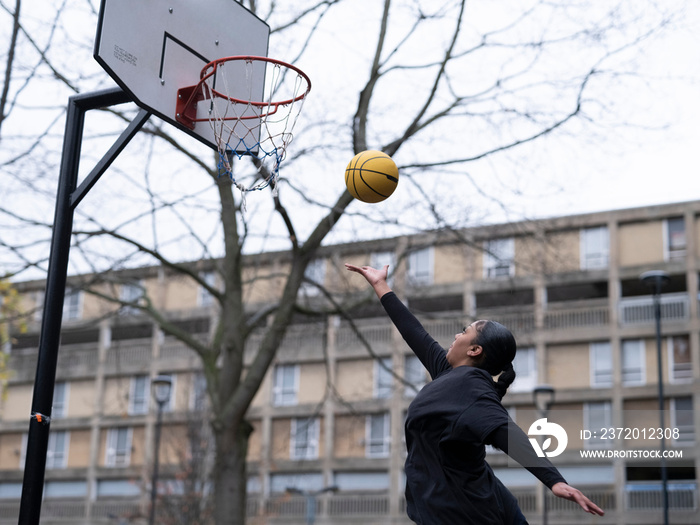 Teenage girl playing basketball outdoors