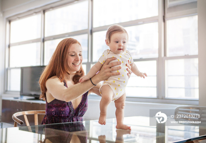 Mother assisting baby girl (6-11 months) with first steps