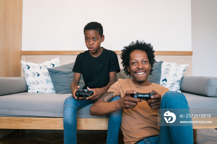 父亲和儿子在家一起玩电子游戏。