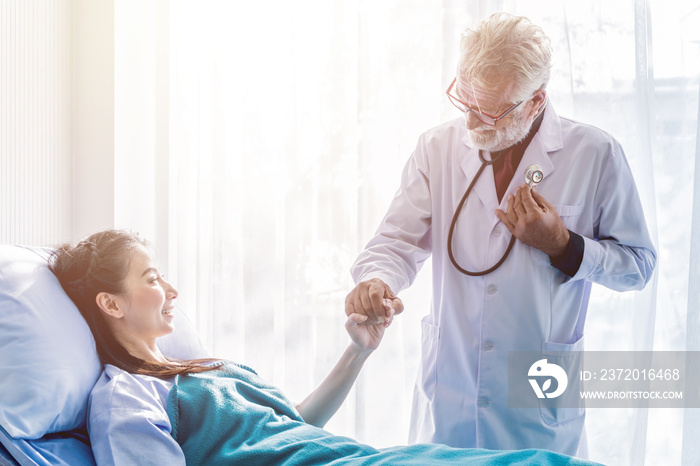 Senior male doctor holding young female patients hand.