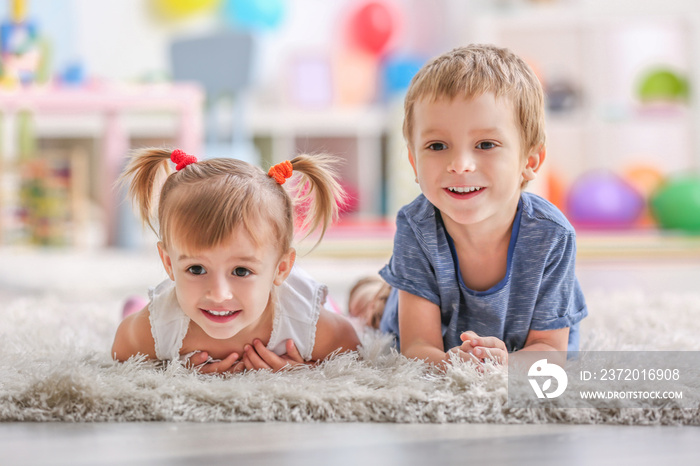 Cute funny children lying on carpet at home