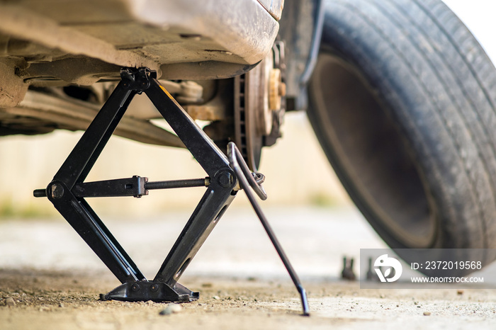 Closeup of a car lifted on jack in process of new wheel tire replacement. Breakdown of a vehicle on 