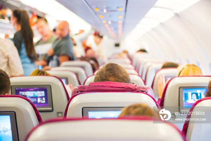 Interior of airplane with passengers on seats and walking the aisle waiting to take off