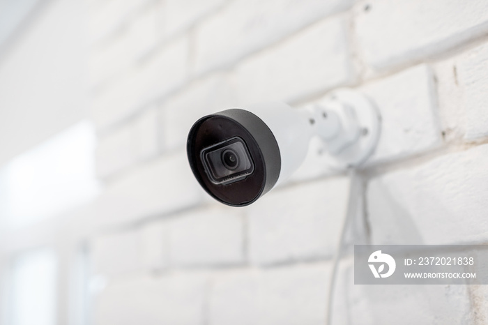 监控ip摄像头安装在室内白砖墙上。家庭视频监控概念