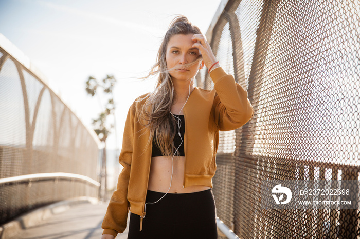 Portrait of confident athlete wearing sports clothing and jacket while standing on footpath