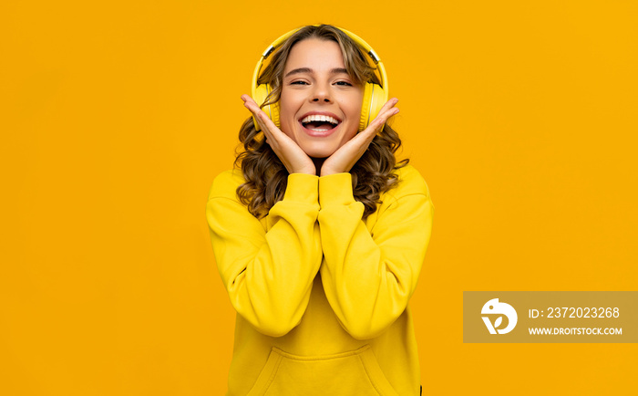 smiling attractive woman listening to music in headphones on yellow background