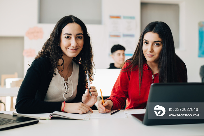 Portrait of confident female students studying together in university