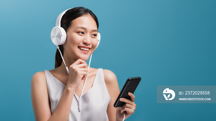 Asian smiling beautiful women blogger wear headphone and holding smartphone isolated in blue color b