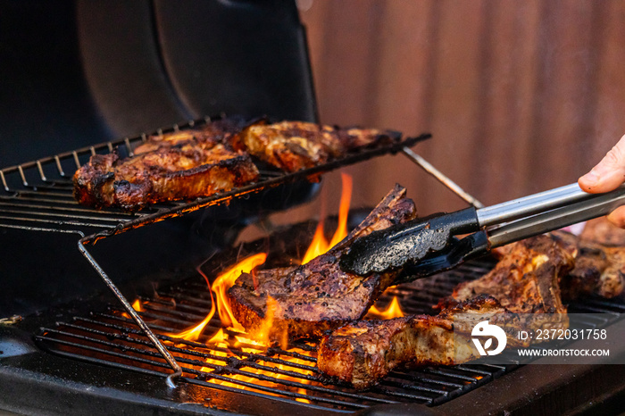 gas grill with grilled meat and grill tongs