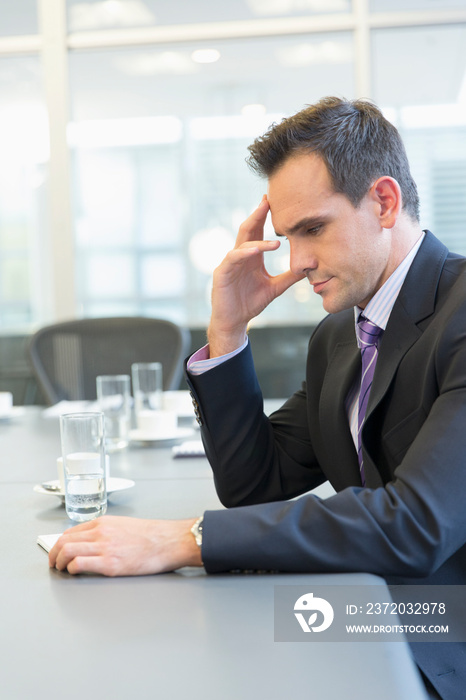 Serious corporate businessman reading paperwork in conference room