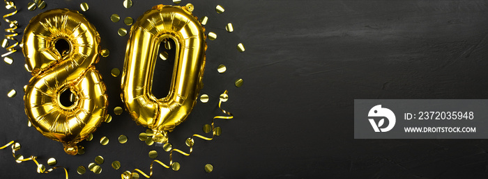 golden foil balloon number eighty. Birthday or anniversary card with the inscription 80. Black concr