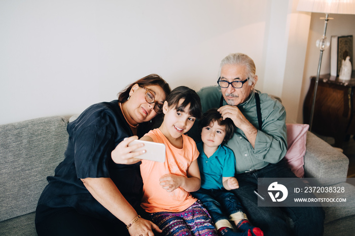 High angle view of girl taking selfie with grandparents and grandson at home