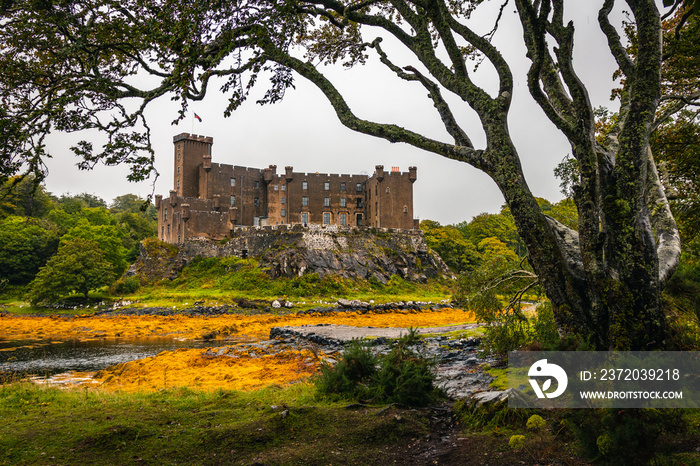 Dunvegan Castle viewed from the gardens, view bordered with tree branches in Dunvegan, Isle of Skye,