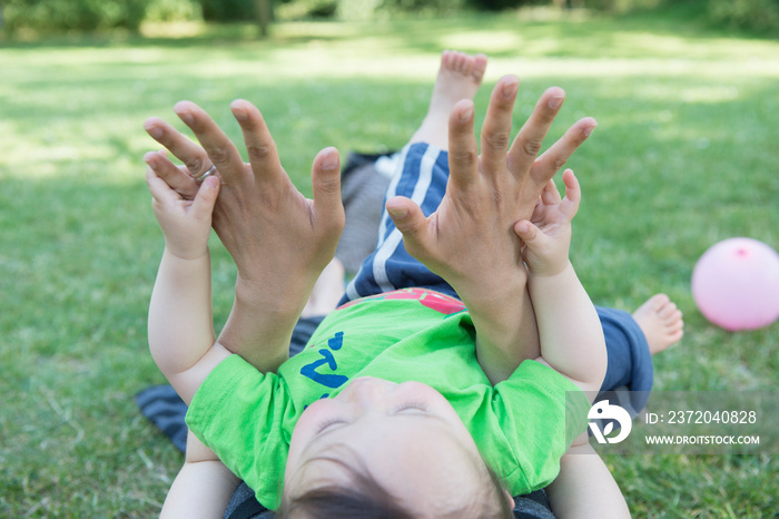 Cropped shot of baby boy touching mothers wedding ring in park