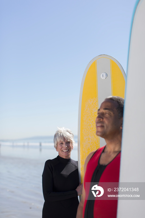 Active senior couple with surfboards on sunny beach