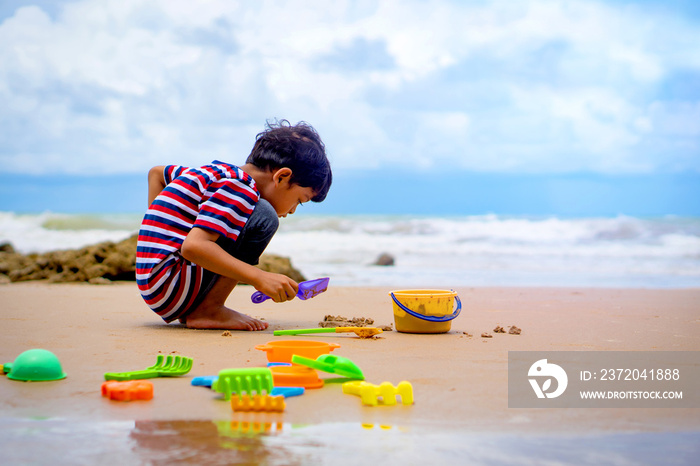 亚洲小男孩在海滩上玩沙子。
