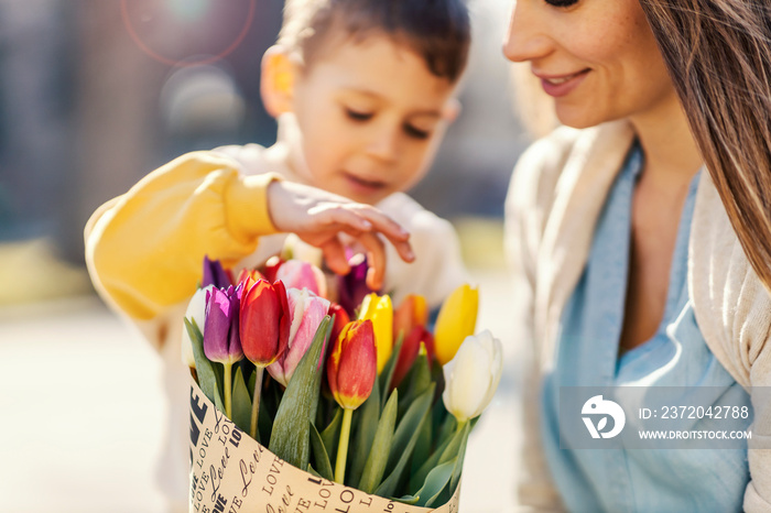 A little boy touching flowers his mother received on mothers day.