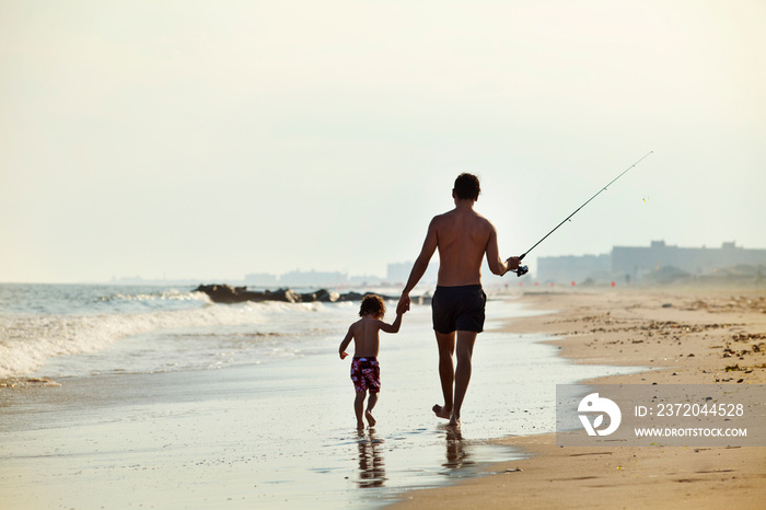 Father walking with daughter (2-3) on beach