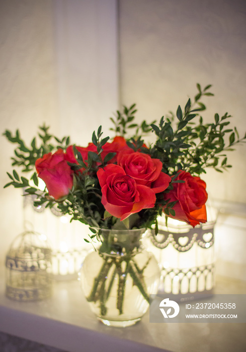 A bouquet of red roses and boxwood in a vase with cells