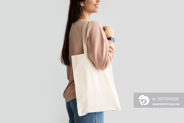 Young woman standing with blank canvas tote bag