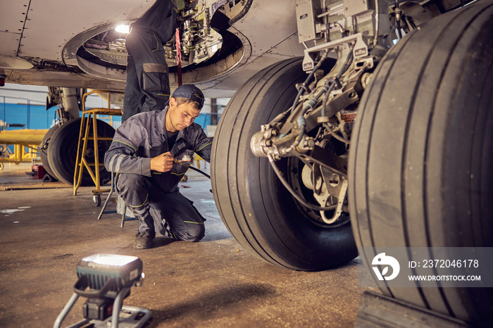 Landing gear airplane in hangar chassis rubber with aviation worker in uniform