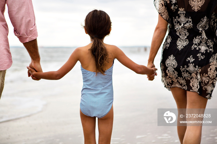 Rear view of girl standing with parents on beach