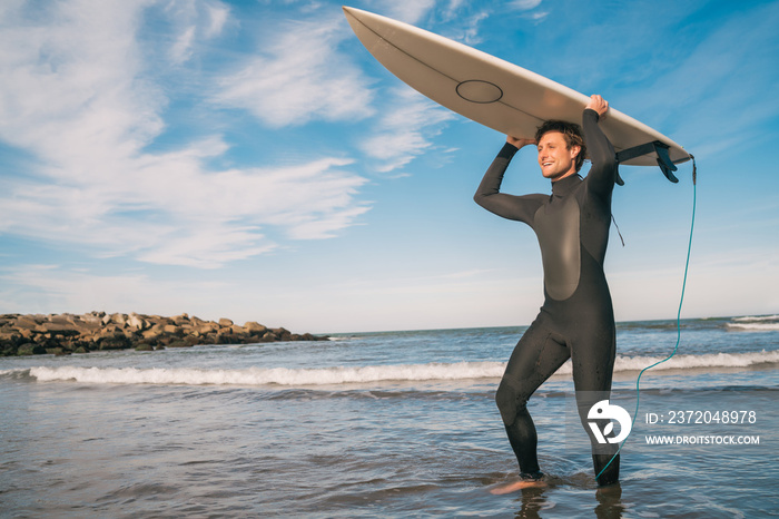 Young surfer holding up his surfboard.