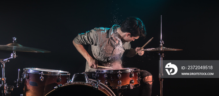 musician playing drums with splashes, black background with beautiful soft light