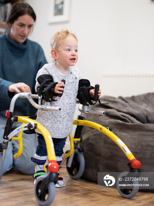 Mother assisting son with cerebral palsy in walking�