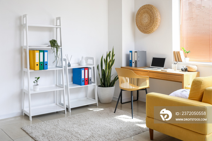 Interior of light office with shelving unit and modern workplace