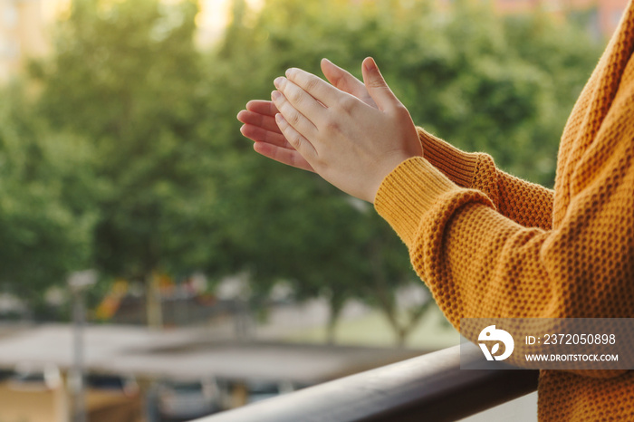 Stock photo of a hands of a young woman clapping from the balcony to support the medical team