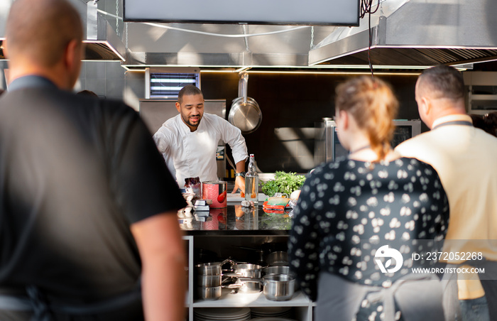 In focus is the chef who conducts a master class in cooking. In the foreground are blurred images of