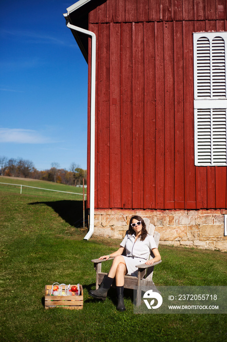 Woman with apple basket sitting on chair against house