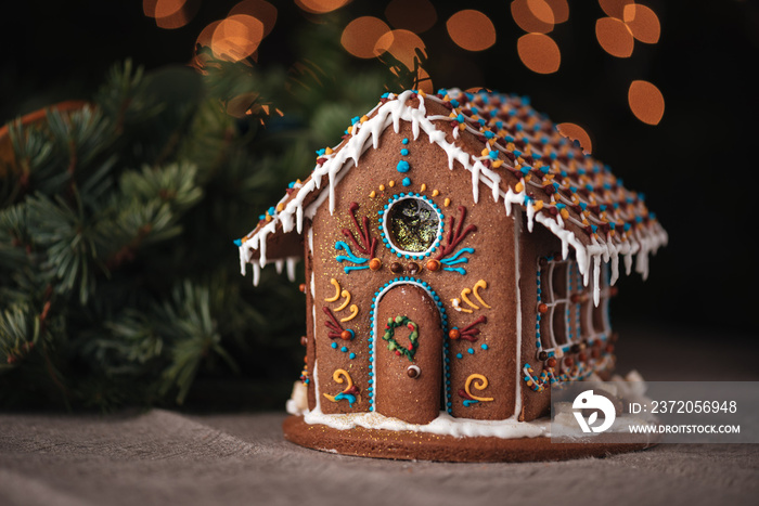 Gingerbread house decorated with colorful glaze and Christmas tree branch