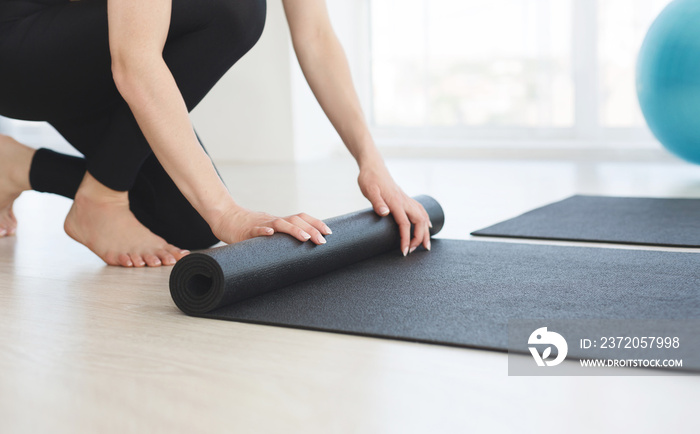 Cropped image of female hands rolling yoga mat