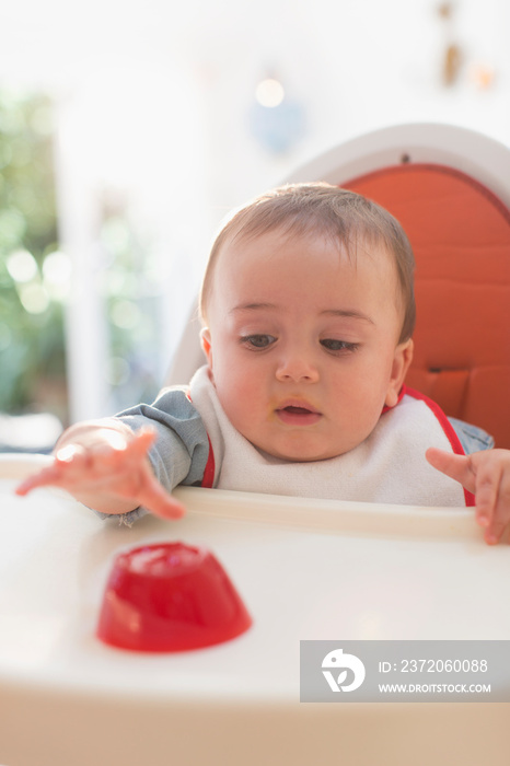 Cute baby boy reaching eating in high chair