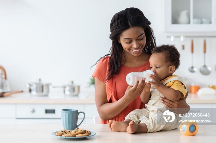 Baby Hydration. Loving Black Mother Giving Water Bottle To Her Infant Child